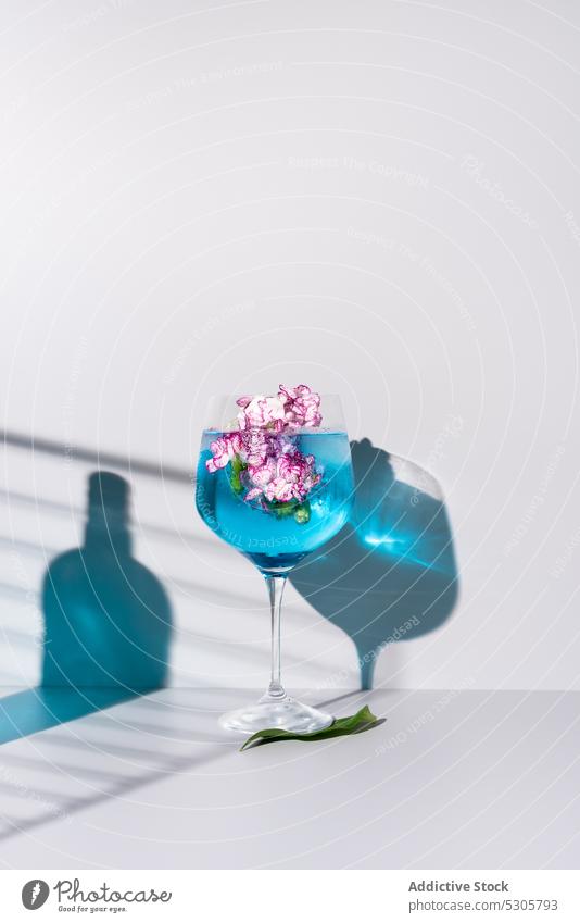 Erfrischender Cocktail mit Eiswürfeln bei Blumen und Flasche trinken Getränk blau Glas Alkohol Erfrischung kalt liquide Schatten Tisch Aperitif Blütezeit lecker