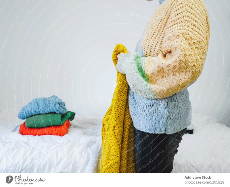 Frau mit gestricktem Pullover in der Nähe des Bettes Stoff anhaben heimwärts organisieren Strickwaren Schlafzimmer lässig gemütlich Outfit Lifestyle Komfort
