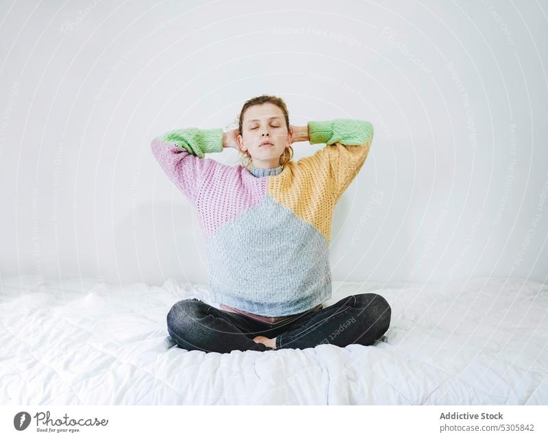 Ruhige Frau meditiert mit geschlossenen Augen auf dem Bett meditieren Yoga Lotus-Pose heimwärts Windstille sich[Akk] entspannen padmasana Augen geschlossen Zen