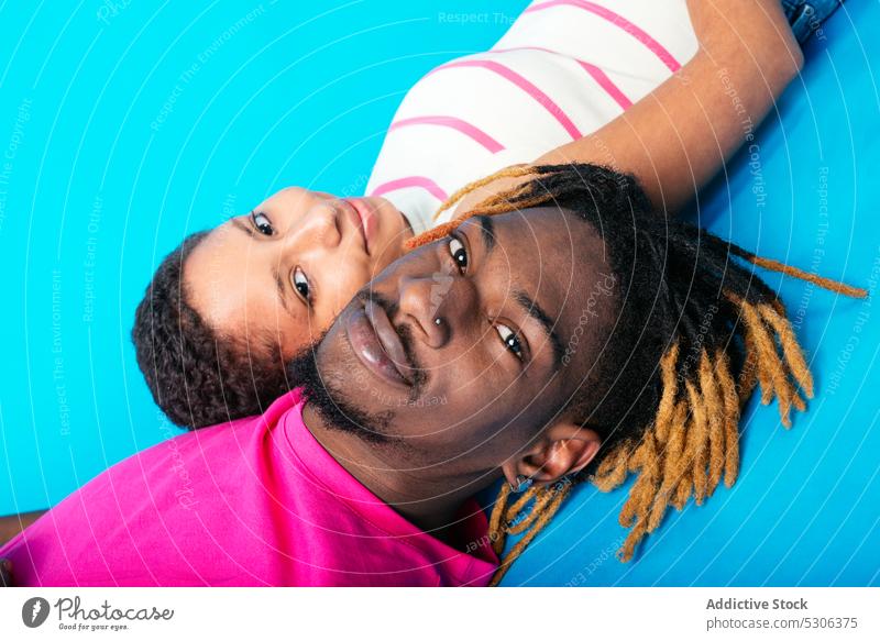 Verschiedenes Paar liegend auf blauem Hintergrund Lügen Liebe Harmonie Studioaufnahme Zusammensein Geliebter Freundin Partnerschaft rassenübergreifend