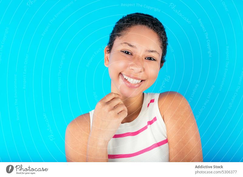 Lächelnde ethnische Frau mit kurzen Haaren schaut in die Kamera Model krause Haare Kurze Haare Streifen Top Studioaufnahme traumhaft positiv Glück jung lässig