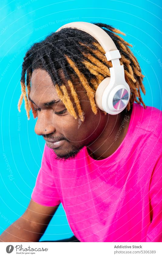 Afroamerikanischer Mann, der mit Kopfhörern Musik hört zuhören berühren Audio Gesang Wiedergabeliste Melodie Studioaufnahme männlich jung Afroamerikaner schwarz
