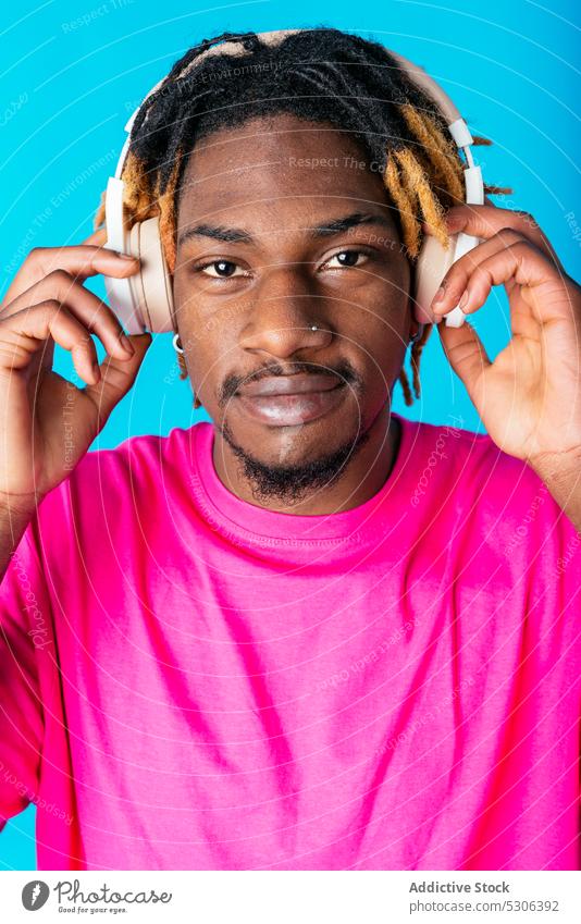 Afroamerikanischer Mann, der mit Kopfhörern Musik hört zuhören berühren Audio Gesang Wiedergabeliste Melodie Studioaufnahme männlich jung Afroamerikaner schwarz
