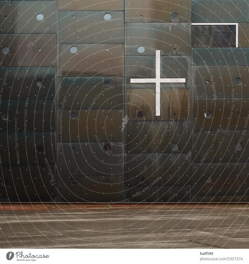 weißes Kreuz an dukeler Metallfassade mit kleinen kreisrunden Glasöffnungen Christliches Kreuz Religion & Glaube Kirche Christentum Symbole & Metaphern