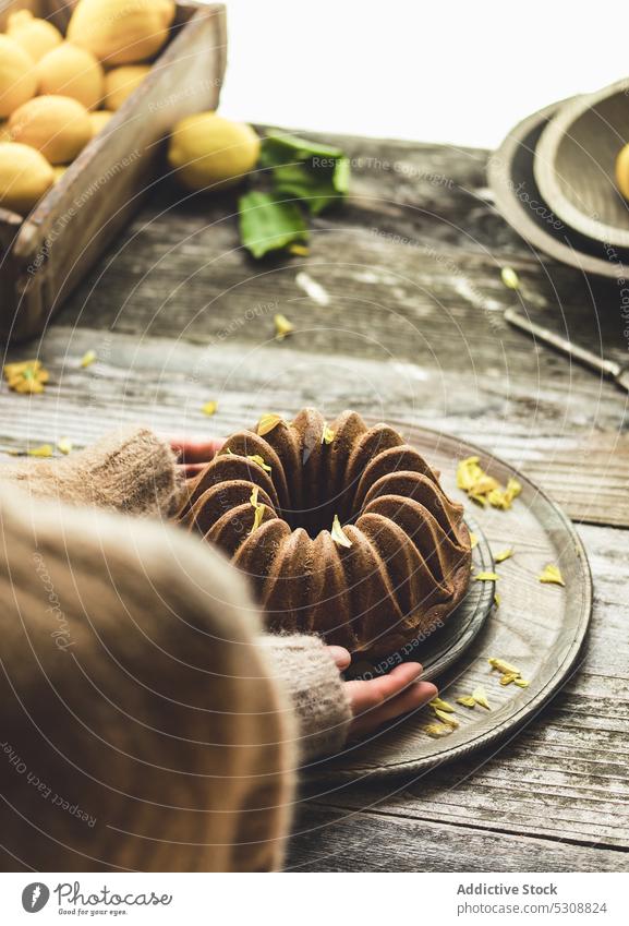 Anonyme Person stellt Kuchen auf Holztisch Tisch Zitrone Teller dienen Spielfigur Dessert Küche zu Hause Zitronenkuchen Veganer-Kuchen pflanzlich Kasten