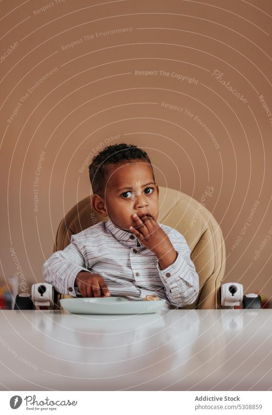 Entzückender Junge isst leckeres Frühstück Kleinkind essen Lebensmittel geschmackvoll niedlich bezaubernd Porträt Kind schwarz Afroamerikaner ethnisch Mahlzeit