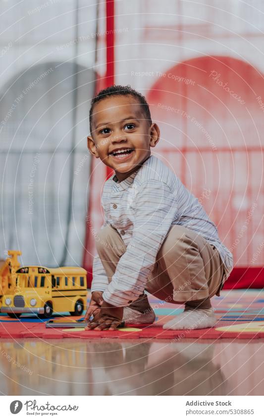 Lächelnder süßer kleiner Junge spielt mit Spielzeug Kleinkind spielen sich[Akk] entspannen Teppich farbenfroh zu Hause niedlich Freude bezaubernd Glück Kind