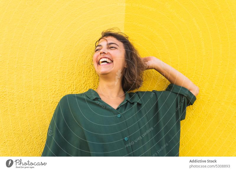 Lächelnde Frau an gelber Wand stehend Stil krause Haare heiter hell Freude farbenfroh Kurze Haare Hemd Farbe jung Lachen Vorschein Individualität Glück