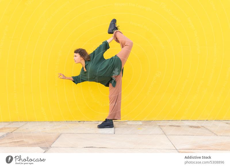 Energetische Frau in Yoga-Pose auf der Straße Gleichgewicht üben beweglich stehender Bogen Mudra Zen Achtsamkeit Dehnung gestikulieren jung Windstille