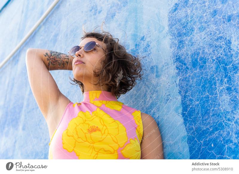 Nachdenkliche Frau mit Sonnenbrille schaut auf der Straße weg Sommer Stil Kurze Haare farbenfroh urban modern Mode Wand trendy selbstbewusst krause Haare