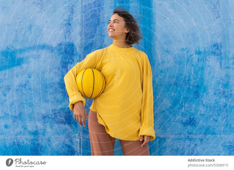 Positive Frau spielt mit Ball gegen blaue Wand werfen Basketball spielen heiter Sportpark Lächeln Glück Spiel jung Spieler Training aktiv Aktivität positiv