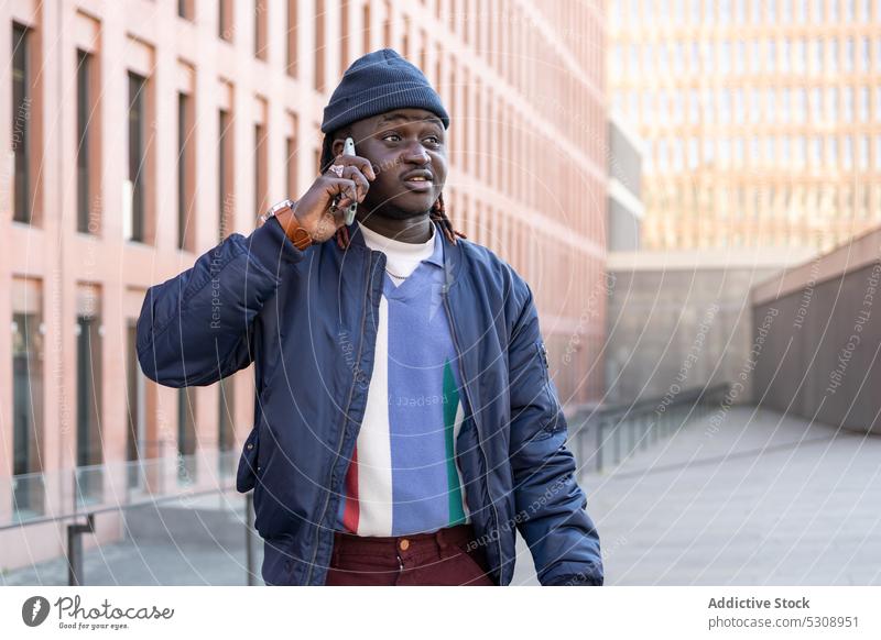 Schwarzer Mann spricht mit Smartphone reden Gespräch sprechen Telefon Anruf Kommunizieren diskutieren Straße Stil Afroamerikaner männlich trendy Outfit