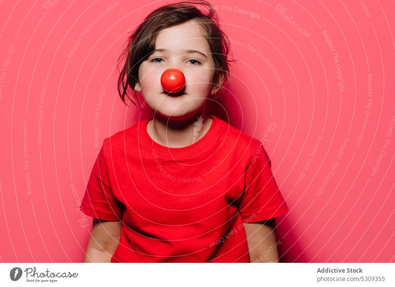 Kleines Mädchen in rotem Freizeitkleid mit roter Nase Clown wenig Kind lässig lustig niedlich Kindheit unschuldig hell charmant T-Shirt reif Porträt Vitamin