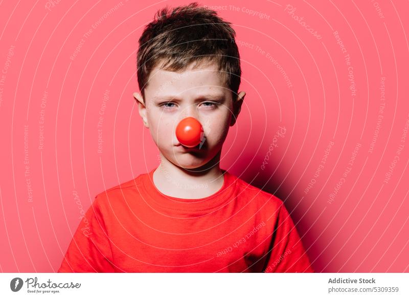 Trauriger Junge mit roter Nase schaut in die Kamera Kind Porträt Clown traurig Windstille lässig unglücklich bezaubernd niedlich T-Shirt jung Kindheit