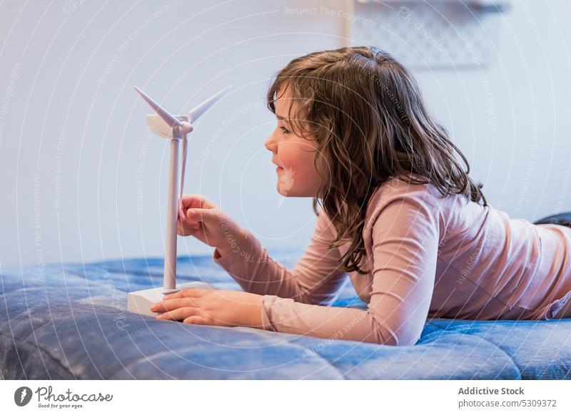 Mädchen spielt mit einer Attrappe einer Windkraftanlage auf dem Bett Kind Spaß haben spielen Schlafzimmer Kindheit Glück Lächeln Freude positiv Lügen Komfort
