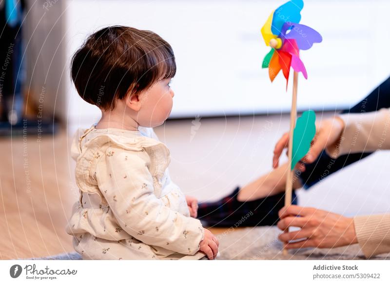 Crop Mutter hält pinwheel beim Spielen mit Tochter Baby Spielzeug Windrad spielen niedlich Zusammensein wenig farbenfroh Mädchen Kind Liebe Mutterschaft