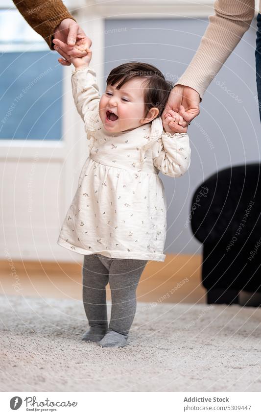 Niedliches kleines Baby, das mit seinen Eltern zu Hause laufen lernt Familie Tochter lernen Spaziergang Händchenhalten abstützen Vertrauen niedlich bezaubernd