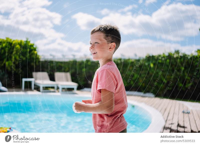 Niedlicher Junge in nasser Kleidung in der Nähe des Pools schaut weg Sommer Beckenrand Resort Feiertag Urlaub Kind Lächeln ruhen Wasser Kindheit bezaubernd
