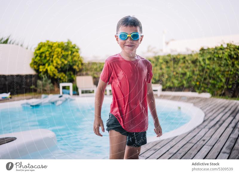 Fröhlicher Junge mit Schwimmbrille am Beckenrand Sommer Pool Kind Urlaub schwimmen Resort Schutzbrille Lächeln Feiertag Wasser Glück heiter Erholung positiv