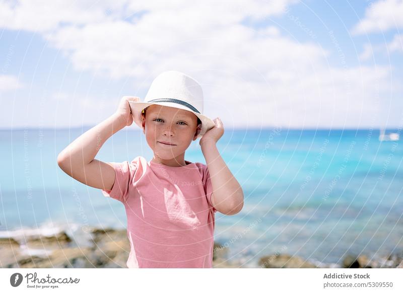 Junge mit Hut steht bei Tageslicht am Meer Blauer Himmel MEER Sommer selbstbewusst Kind Natur jung Kindheit Lifestyle Strand sorgenfrei außerhalb Sommerzeit