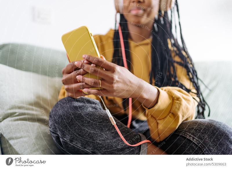 Anonyme schwarze Frau mit Kopfhörern, die ein Videogespräch auf einem Smartphone führt Videoanruf Video-Chat benutzend Kommunizieren heimwärts Gespräch ethnisch