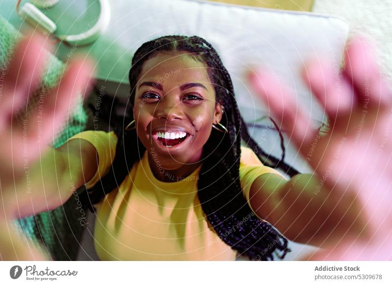 Fröhliche schwarze Frau streckt die Hände in die Kamera und lächelt positiv sich[Akk] melden Lächeln Liege Lügen heiter Geflecht Glück sorgenfrei