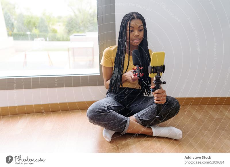 Schwarze Frau nimmt Podcast mit Mikrofon auf Aufzeichnen Smartphone Lächeln Blogger vlog Kommunizieren Audio jung ethnisch Afroamerikaner heimwärts Ausstrahlung
