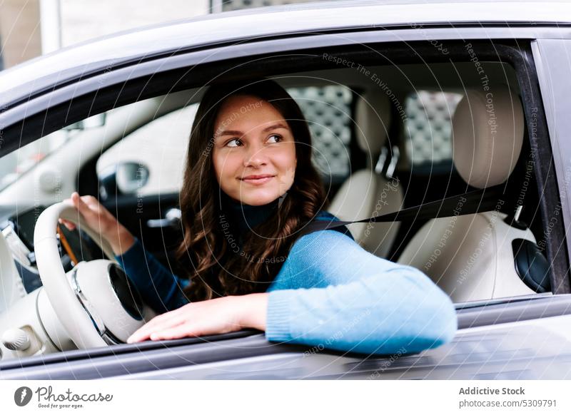 Positive Frau am Steuer eines Autos sitzend Lächeln Glück Fahrer Laufwerk PKW Automobil Fahrzeug Lenkrad Verkehr Ausflug jung Bluse Streifen weiß modern positiv
