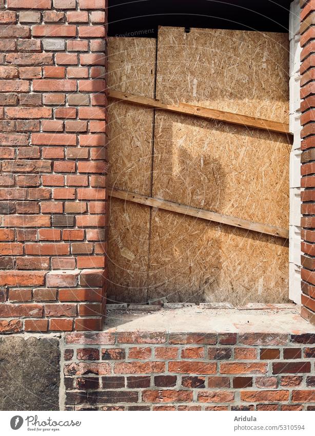 Altes Backsteinhaus, Fensteröffnug mit OSB-Platten versperrt Haus Mauer Wand Holz verrammelt kein Zugang kein Zutritt alt Altbau Verfall Bauwerk Gebäude