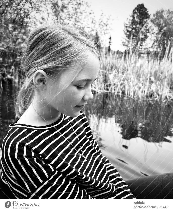 Mädchen sitzt in einem Boot mit See und Ufer im Hintergrund und schaut nach unten s/w Tretboot Kind Wasser Kopf Streifenshirt Freizeit & Hobby Ausflug