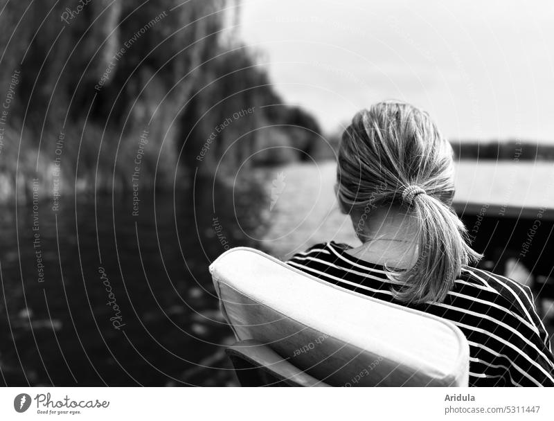 Rückenansicht | Mädchen sitzt im Tretboot auf einem See mit Ufer s/w Kind Wasser Pferdeschwanz Kopf Frisur Streifenshirt Freizeit & Hobby Ausflug Außenaufnahme