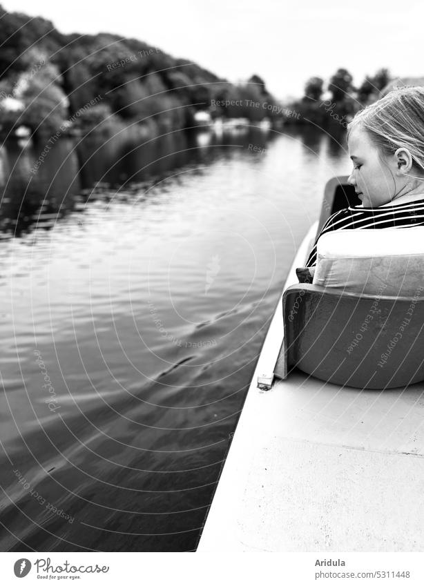 Mädchen sitzt im Tretboot auf einem See mit Ufer und schaut auf das Wasser s/w Kind Rückenansicht Kopf Streifenshirt Freizeit & Hobby Ausflug Außenaufnahme