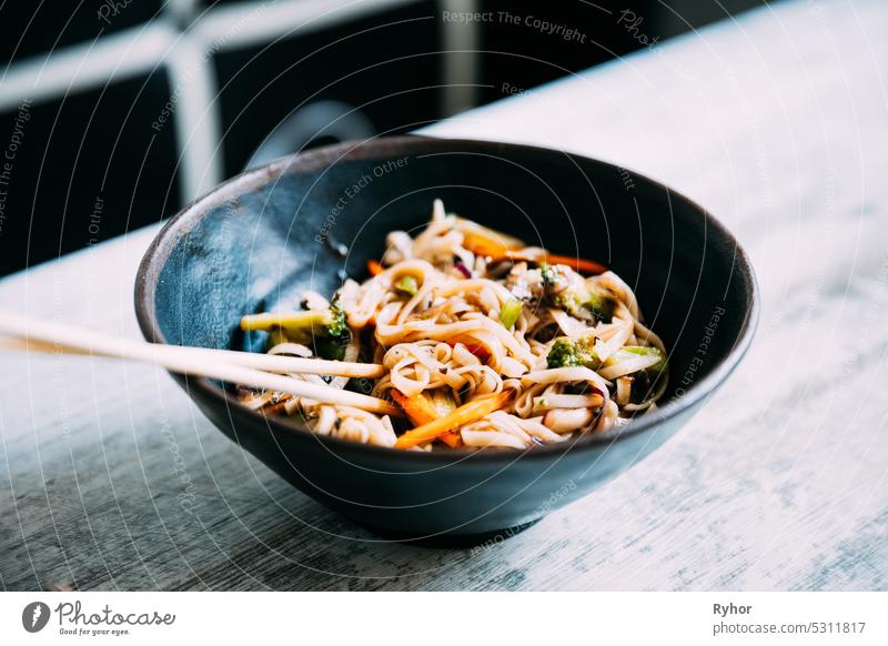 Ansicht osf asiatische Nudeln udon mit Schweinefleisch Nahaufnahme in einer Schüssel auf dem Tisch schwarz Schalen & Schüsseln Peperoni Chinesisch Essstäbchen