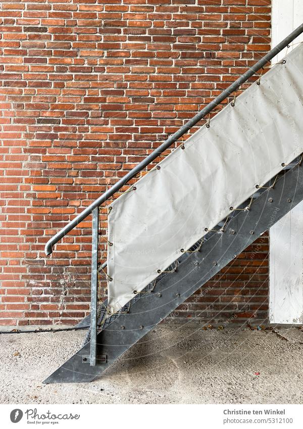 Eine Metalltreppe mit Sichtschutz vor einer geflickten Klinkerfassade Treppe Außentreppe Fassade Backsteinwand Klinkerwand Wand alt geflickte Klinkerwand