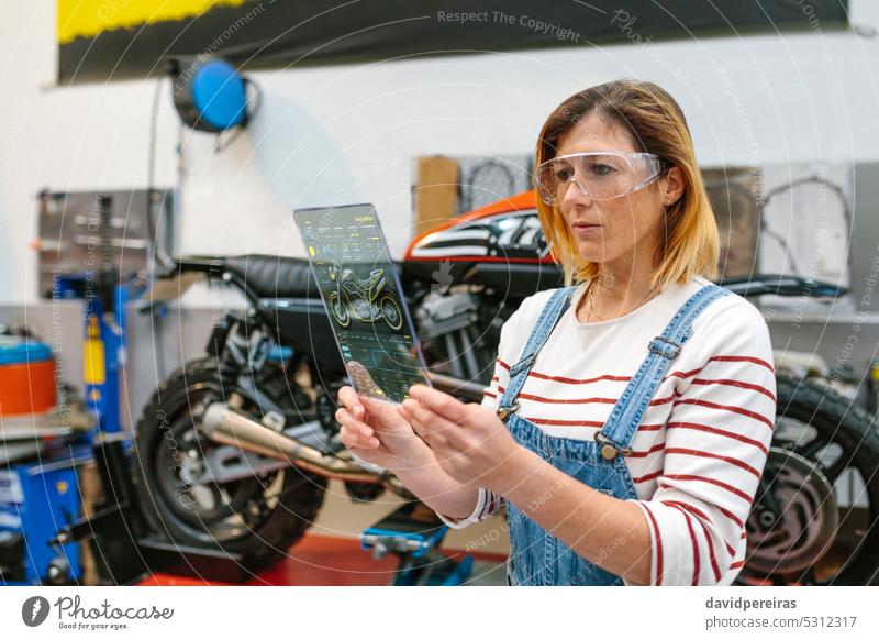 Mechanikerin mit transparentem Digital-Tablet und Motorrad-Diagnose-App Frau benutzend Tablette Diagnostik Bildschirm Schnittstelle durchsichtig Blick
