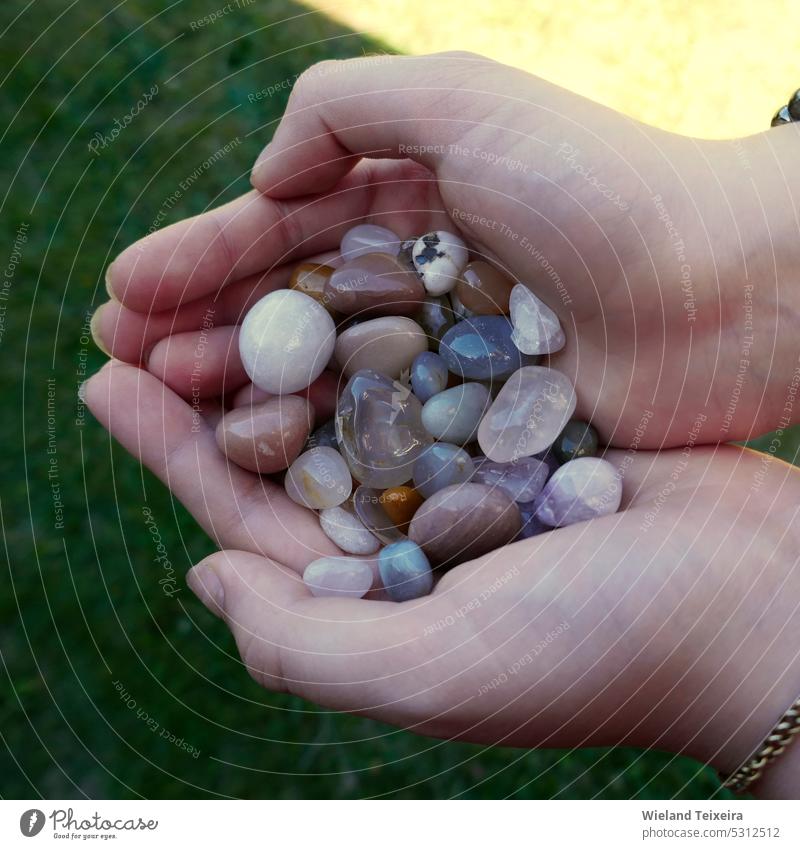 Tumble fertige Mischung aus Halbedelsteinen in den Händen eines Mädchens Steine braun farbenfroh Farbe Natur schön natürlich im Freien Nahaufnahme Kristalle