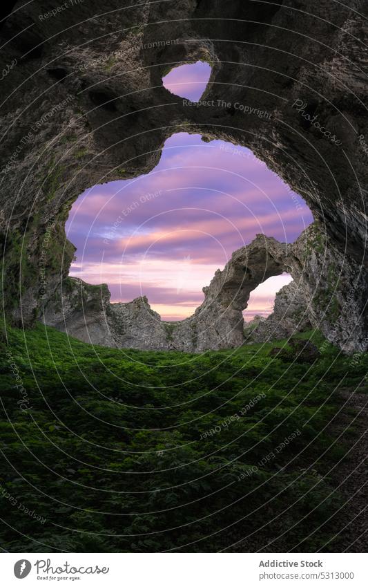 Doppellochhöhle in bergigem Gelände vor Sonnenuntergang Höhle Golfloch Berge u. Gebirge felsig Formation grün Gras farbenfroh malerisch Landschaft lebhaft Farbe