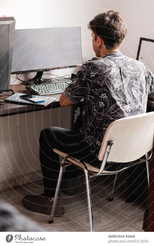 Mann arbeitet am Computer im Heimbüro freiberuflich Arbeitsbereich Arbeitsplatz Telearbeit Smartphone benutzend Gerät Job heimwärts Internet Schreibtisch Stuhl