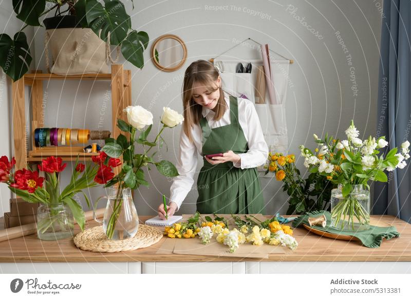 Glückliche Blumenhändlerin beim Stöbern im Smartphone Frau Browsen zuschauend Orden Werkstatt Laden Arbeit schreiben Gespräch Empfang verkaufen Floristik