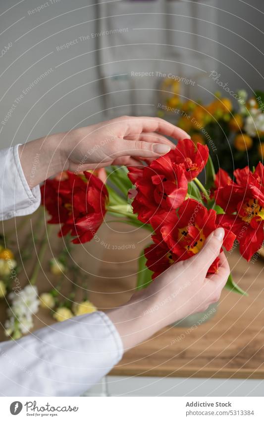 Crop-Frau mit roten Blumen Blumenhändler Haufen Blumenstrauß Arbeit geblümt frisch Blüte Blütezeit Floristik Laden Arbeitsplatz Werkstatt professionell Job
