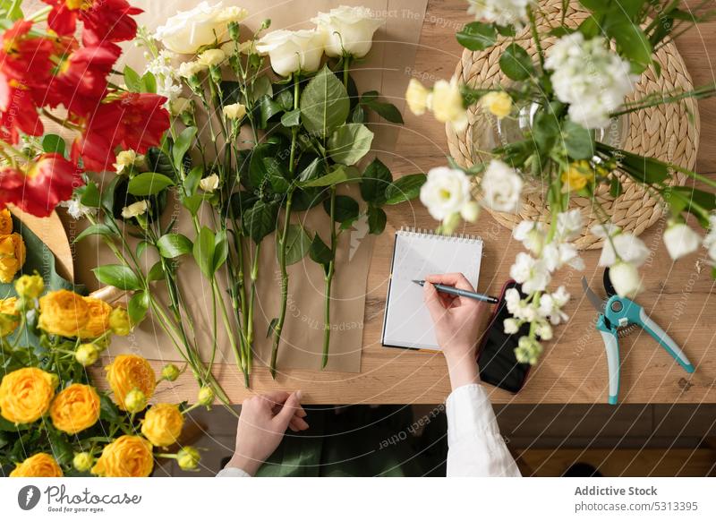 Florist mit Notizen im Notizbuch Frau Blumenhändler zur Kenntnis nehmen Arbeit Floristik Blüte geblümt schreiben Blumenstrauß Notebook Arbeitsplatz Blütezeit