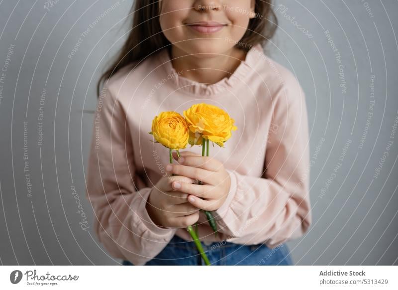 Stehendes Mädchen mit gelben Hahnenfußblüten Frau Blume Glück Lächeln Blütezeit froh geblümt frisch Kind heiter Blumenstrauß Ranunkel Flora positiv Pflanze