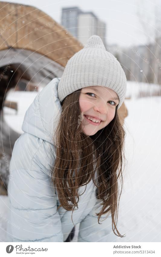 Lächelndes Mädchen in Winterkleidung im Schnee stehend Park warme Kleidung heiter Großstadt positiv Glück kalt Kind froh Freude Oberbekleidung Optimist Straße