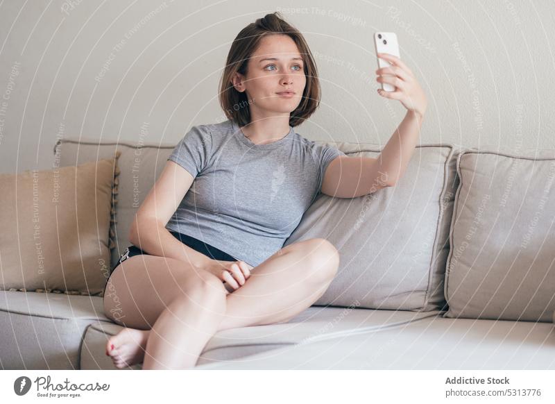 Charmante Frau nimmt Selfie auf Smartphone auf Sofa Kälte heimwärts Selbstportrait Wochenende ruhen benutzend Liege Komfort Wohnzimmer gemütlich Apparatur Gerät