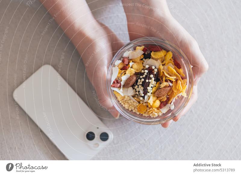 Crop Person mit gesunder Snackschale Müsli Smartphone Container Nut Gesundheit Frühstück Samen Lunch-Box Vitamin Lebensmittel gesunde Ernährung natürlich frisch
