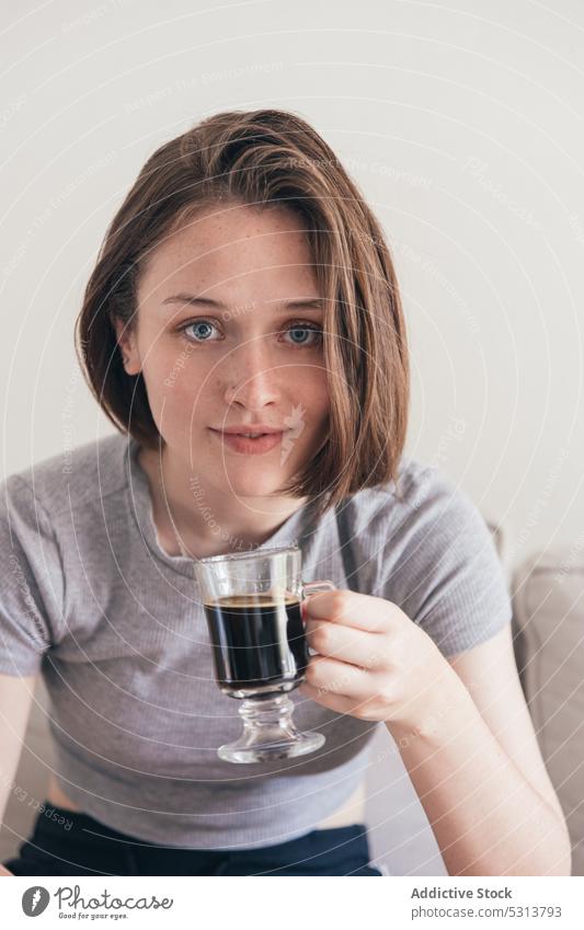 Zufriedene Frau mit einer Tasse Kaffee auf dem Sofa heimwärts trinken positiv Frühstück ruhen jung Liege Glück lässig räkeln Getränk heimisch Inhalt Freude