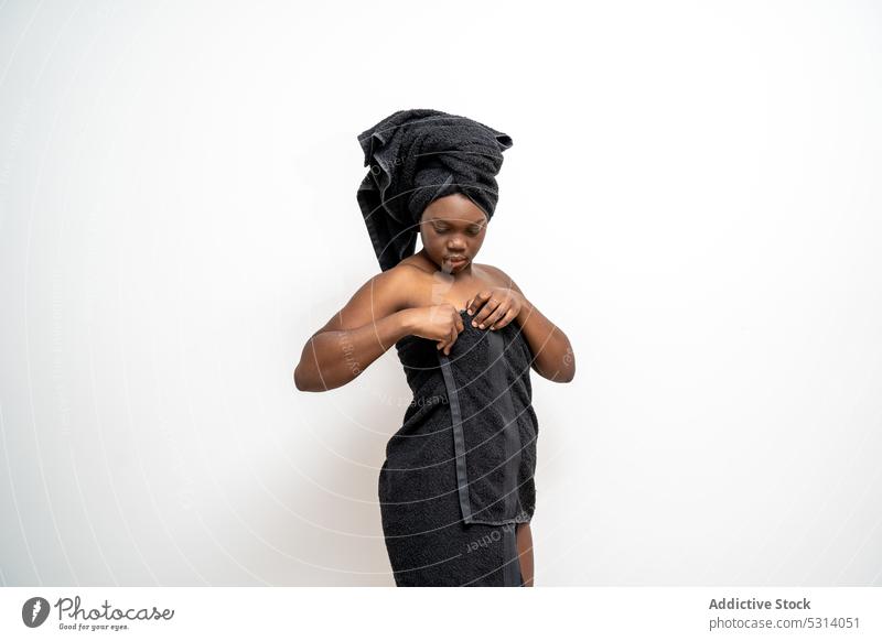 Ruhige schwarze Frau wickelt sich in Handtuch umhüllen Dusche Bad Fokus Verfahren Hygiene Spa Sauberkeit jung ethnisch Wellness Pflege Windstille natürlich