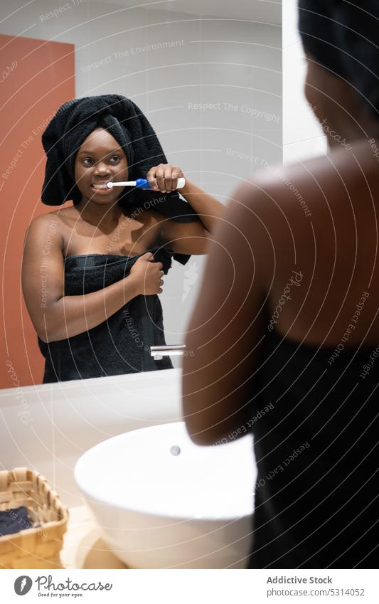 Schwarze Frau beim Zähneputzen im Badezimmer Bürste Hygiene Routine täglich Verfahren Spiegel Waschbecken Reflexion & Spiegelung Morgen heimwärts Sauberkeit