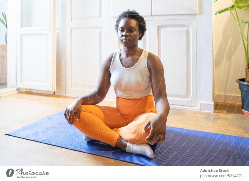 Schwarze Frau beim Yoga auf der Matte üben Lotus-Pose Unterlage meditieren Zen heimwärts Konzentration Sportbekleidung Windstille padmasana Afroamerikaner