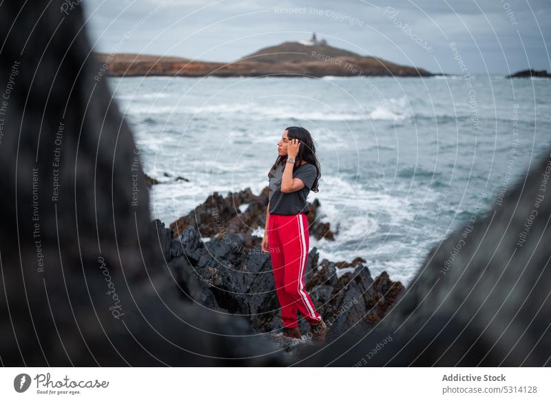 Junge Frau steht auf einem Felsen am Meer Klippe MEER Küste Berge u. Gebirge Natur felsig schäumen Ufer Republik Irland Himmel Glück winken wolkig jung Wasser